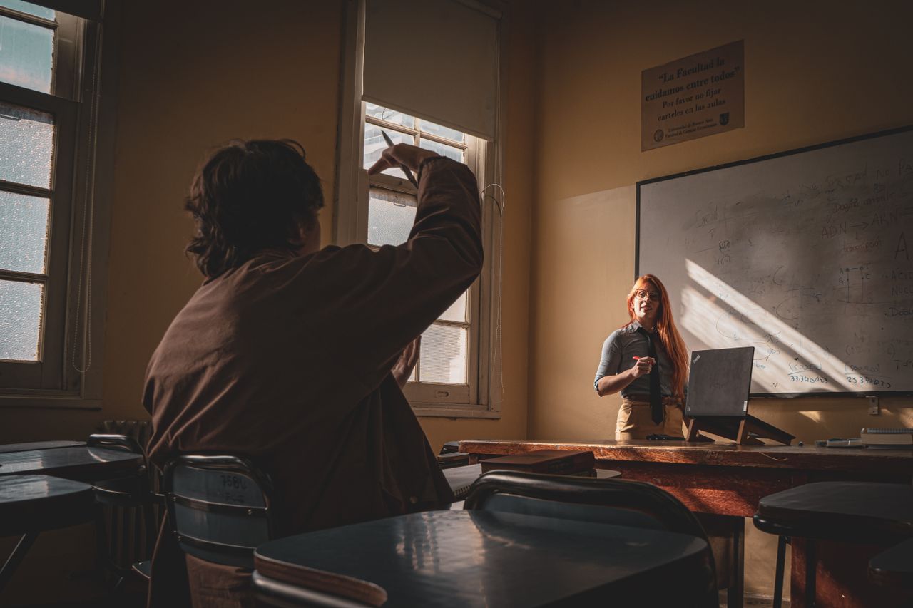A teacher interacts with a student in a sunlit classroom setting, fostering learning and engagement.