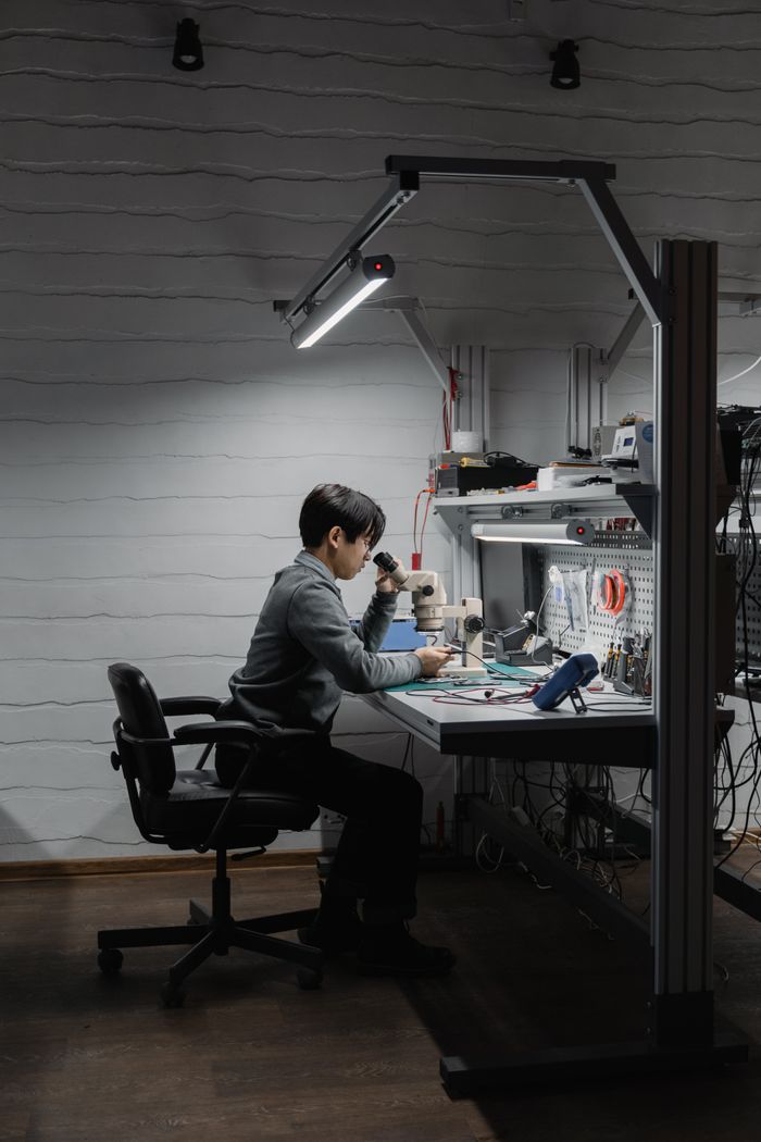 Engineer working at a desk in a technology lab with various electronic devices.